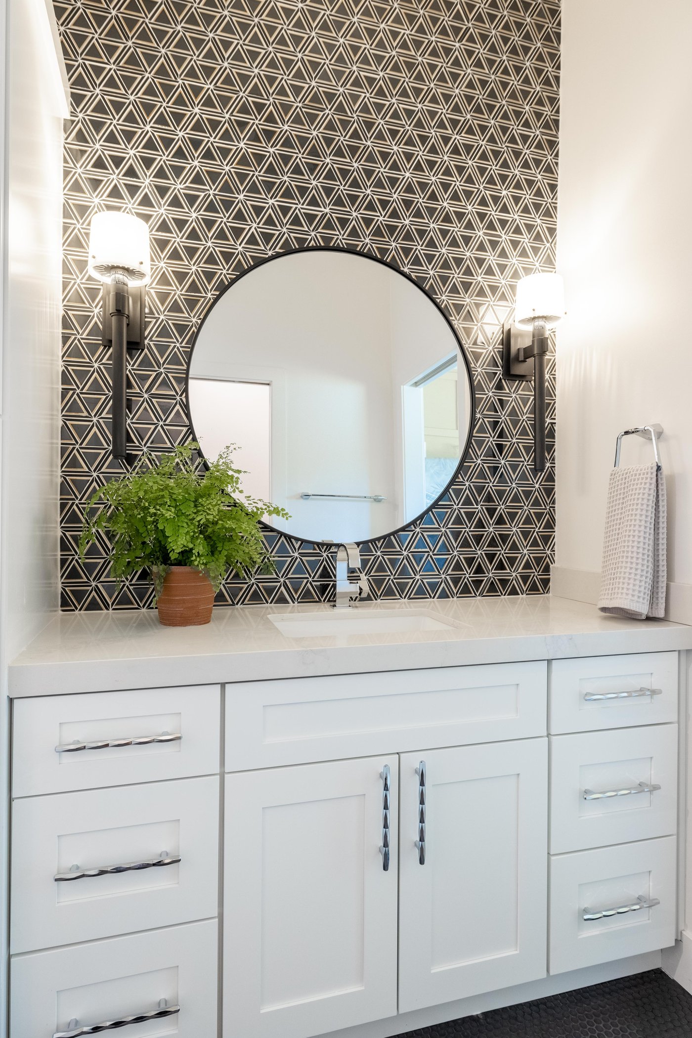 ADU bathroom with geometric tile accent wall and round mirror, Trinity Homes Remodeling project